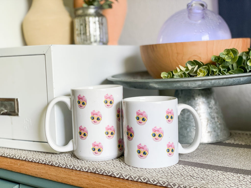 Two white mugs on a counter with baby's face multiplied around the mug in rows. Final product comes with images provided by customer. Shown in 15oz size with 4 rows of faces and 11oz size with 3 rows of faces.