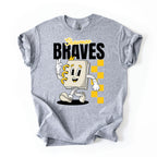 A heather gray short-sleeve t-shirt with a graphic print of a cartoon character notebook with yellow accents, the text 'Shawnee BRAVES' in black and yellow, and a yellow checkered pattern, shown on a plain white background.